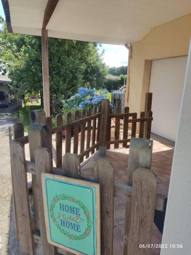 d'une clôture en bois avec un panneau indiquant une maison dans l'établissement Studio Cosy proche Grand-Champ Home Sweet Home, à Plumergat