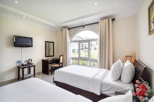 a hotel room with two beds and a window at La Bonita Hotel and Apartments in Ho Chi Minh City