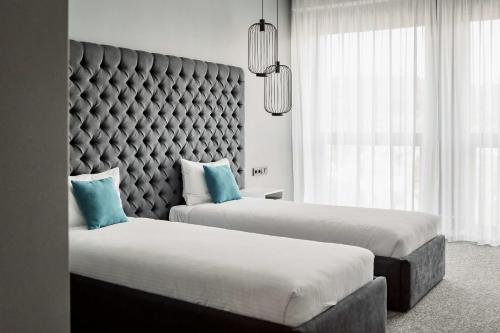 two beds in a hotel room with a large headboard at City Inn Lviv Smart Hotel in Lviv