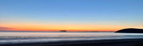 a sunset over a beach with rocks in the water at Apartment 18 Hill View in Brean