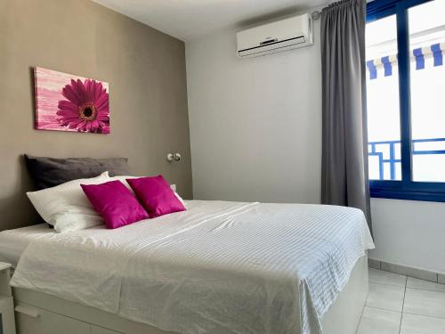 een slaapkamer met een groot bed met roze kussens bij Apartment mit Traumblick in Taurito