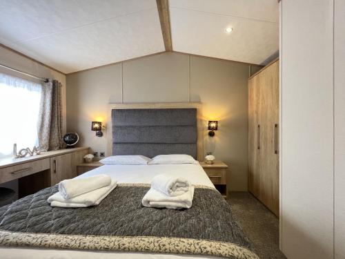 a bedroom with a large bed with towels on it at Stewarts Resort Lodge 3 in St Andrews