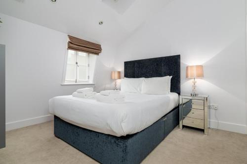A Stunning Three Bedroom Home in Mayfair في لندن: غرفة نوم بسرير كبير مع شراشف بيضاء ونافذة
