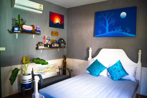 een slaapkamer met een wit bed met blauwe kussens bij Hostel and Music Bar Bros in Pai