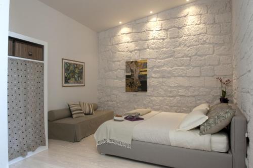 オルヴィエートにあるアパルタメント マナッセイの白レンガの壁のベッドルーム(ベッド1台、ソファ付)
