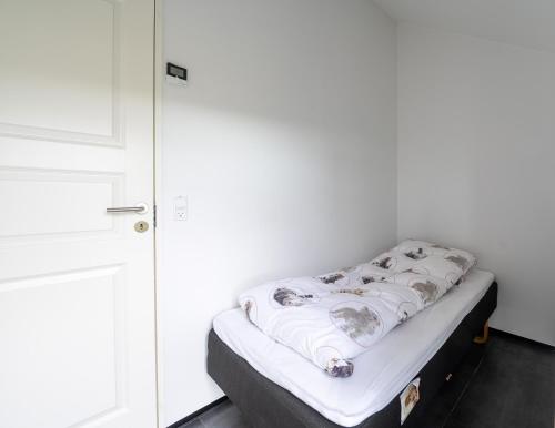 a bed in a room with a white wall at Peaceful Nature Escape in Skálavík - 3BR - Parking in Skálavík