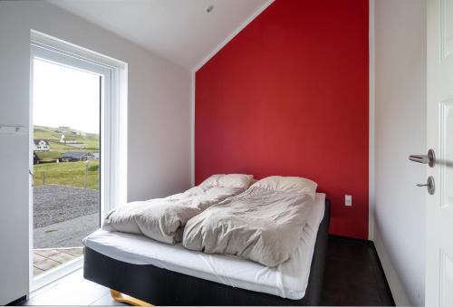 a bed in a room with a red wall at Peaceful Nature Escape in Skálavík - 3BR - Parking in Skálavík