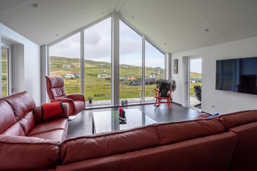 a living room with a couch and a large window at Luxurious cabin / 3 BR / Scenic village in Skálavík