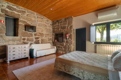 sypialnia z 2 łóżkami i kamienną ścianą w obiekcie Quinta De Calvelos w mieście Vieira do Minho