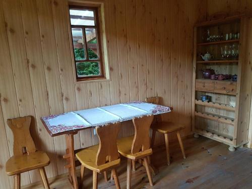 einen Tisch in einem Zimmer mit Stühlen und einem Fenster in der Unterkunft Malastow Mały Domek in Małastów