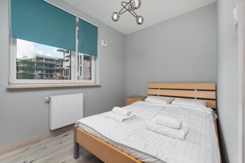 - une chambre avec un lit doté de draps blancs et une fenêtre dans l'établissement Łopuszańska 55 by Homeprime, à Varsovie