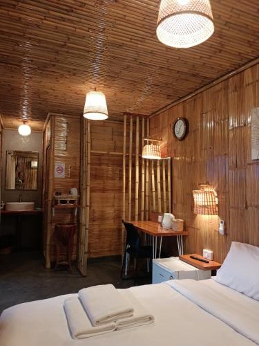 a bedroom with a bed and a table and a clock at สวนเกษตรรักษ์ไผ่ Bamboo Conservation Farm in Surin