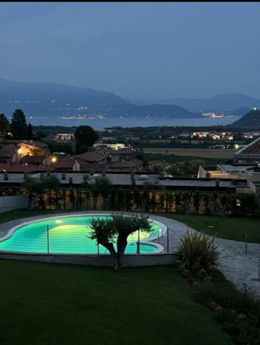 a swimming pool with a tree next to a building at Bilocale in residence vista lago con piscina in Polpenazze del Garda