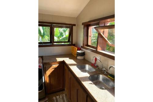 una cucina con un lavello e due finestre di Casa de frente para a praia - Arraial d' Ajuda a Arraial d'Ajuda