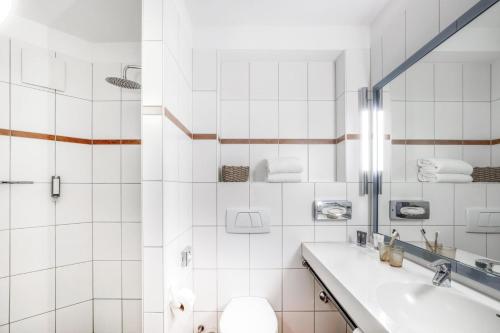 a white bathroom with a sink and a toilet at Select Hotel Oberhausen in Oberhausen