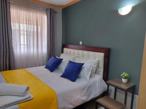 a bedroom with a large bed with blue pillows at Parkview apartments in Nakuru