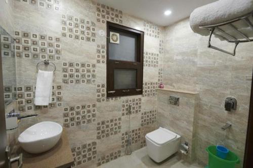 a bathroom with a toilet and a tv on the wall at Kartikay hotel in Hisār