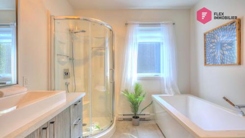 y baño con ducha, bañera y lavamanos. en La Villa Éden-SPA de Portneuf / Relaxation and activities aplenty en Pont-Rouge