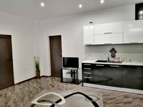 a kitchen with white cabinets and a chair in a room at Апартамент ЗАПАД in Kazanlŭk