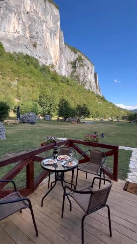 a patio with two chairs and a table on a wooden deck at Etno apartmani Komarnica in Šavnik