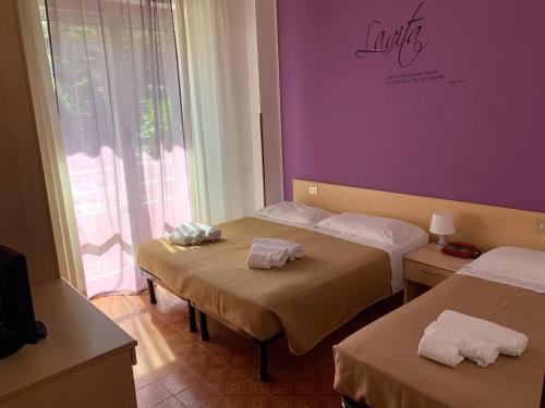 Habitación con 2 camas y pared púrpura. en Amica, en Salsomaggiore Terme