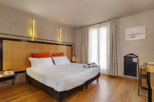 a bedroom with a large white bed with orange pillows at Hotel Ancora in Verbania