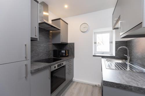 a kitchen with white cabinets and a sink and a window at Lovely City Centre 1 bedroom flat. in Perth