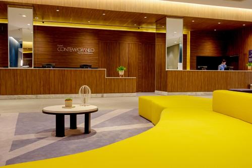 a lobby with a yellow couch and a table at Hotel Contemporâneo - Royal Palm Hotels & Resorts in Campinas
