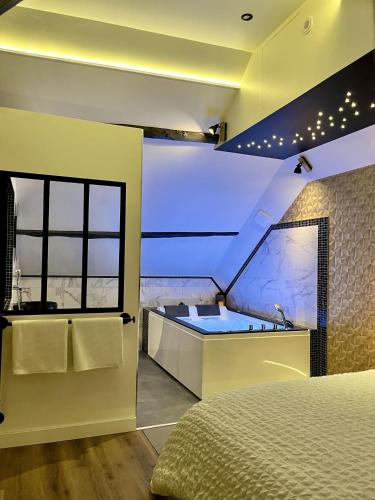 1 dormitorio con bañera, 1 cama y lavamanos en L'Intemporel Suite Spa, en Champagne-sur-Oise