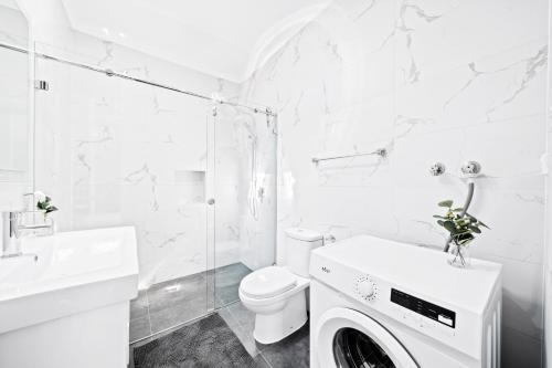 W białej łazience znajduje się pralka. w obiekcie New 2 Bedroom House 500m to Mall with Free Parking w mieście Bankstown