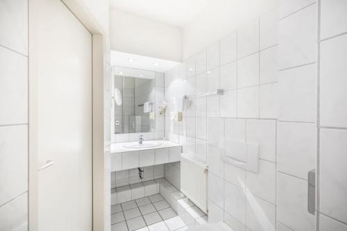 Baño blanco con lavabo y espejo en Hotel Elisenhof Mönchengladbach, en Mönchengladbach
