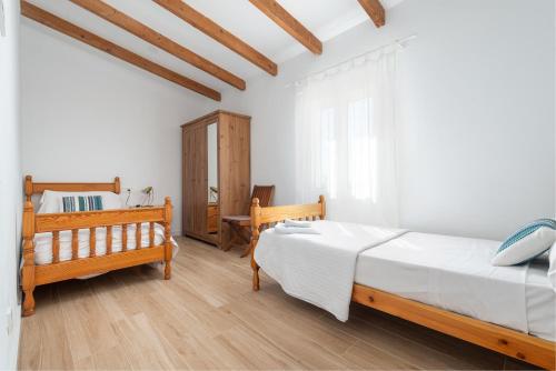 a white bedroom with two beds and a table at Ca na Menuda in Sencelles