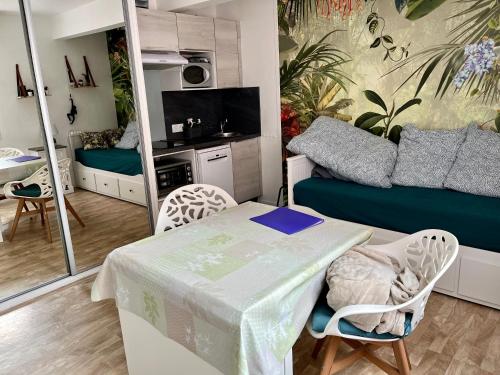 a small living room with a table and a couch at Sénane - Joli studio à 50m de la plage, parking in Courseulles-sur-Mer