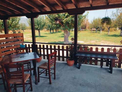 eine Veranda mit Bänken, Tischen und einem Zaun in der Unterkunft ACHILLEAS PEACEFUL PLACE in Skála Sikiás