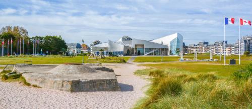 a playground in a park with a building and a flag at Sénane - Joli studio à 50m de la plage, parking in Courseulles-sur-Mer