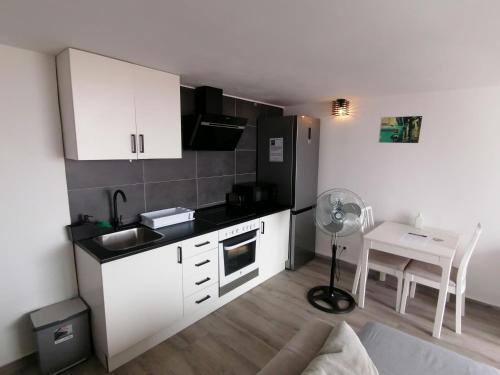 a kitchen with white cabinets and a table with a fan at BRISAMAR Apartamento con aire acondicionado in Torremolinos
