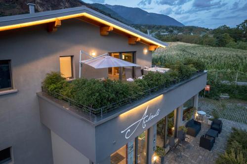 una vista exterior de una casa con un patio al aire libre con sombrilla en Arbulé Agriturismo & Spa Valtellina en Poggiridenti