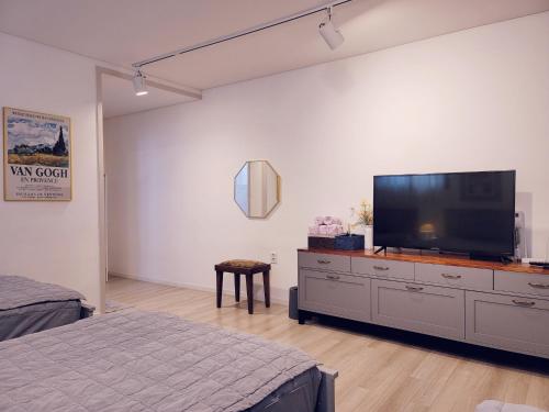 a bedroom with a large flat screen tv on a dresser at Picasso Guesthouse in Mokpo