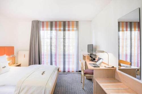 Habitación de hotel con cama y escritorio con ordenador en acora Düsseldorf Living the City - Apartments en Düsseldorf