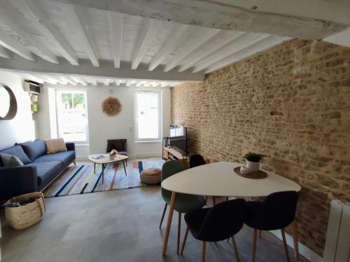 a living room with a table and a brick wall at La Nacre de Saint Aubin sur Mer in Saint-Aubin-sur-Mer