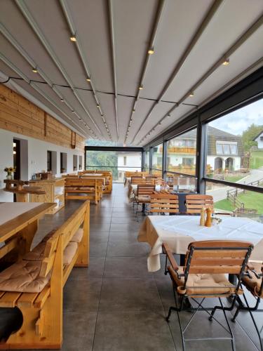 un restaurante con mesas y sillas de madera y ventanas en Guesthouse Jelenov greben en Podčetrtek
