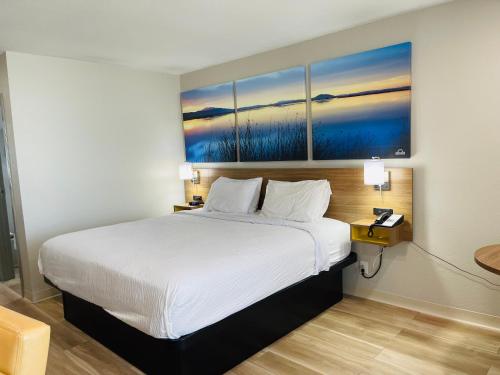 a bedroom with a white bed with a painting on the wall at Days Inn by Wyndham Killeen Fort Hood in Killeen