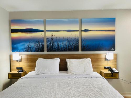基林的住宿－Days Inn by Wyndham Killeen Fort Hood，卧室配有一张壁挂着四幅画作的床