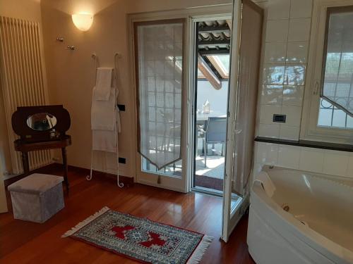 a bathroom with a tub and a glass door with a balcony at Relais Juliette in La Morra