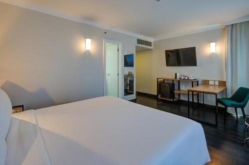 a hotel room with a white bed and a desk at Park Inn by Radisson Berrini in Sao Paulo