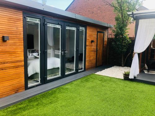 a garden room with sliding glass doors and a bedroom at MeeZee Pearl Double Bed Lodge With Free Parking in Manchester