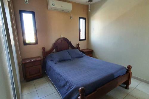 a bedroom with a bed with a blue blanket and two windows at Excelente Depto para 4 pers en zona estratégica in Santiago del Estero