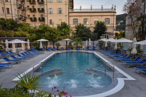 a pool at a hotel with chairs and umbrellas at Hotel Astoria in Stresa