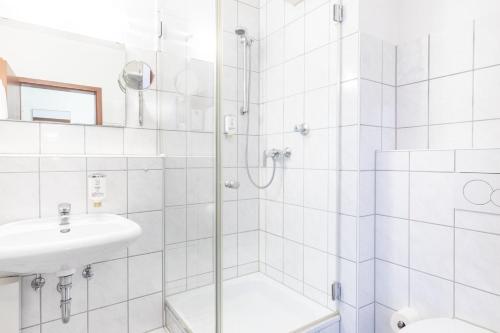 a white bathroom with a shower and a sink at acora Düsseldorf Living the City - Apartments in Düsseldorf