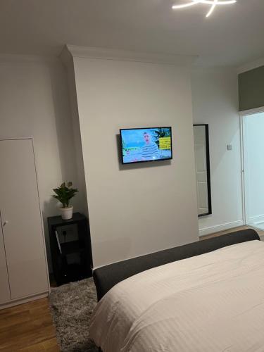 a bedroom with a bed and a flat screen tv on the wall at Comfortably furnished 2 bedroom home in Bolton in Bolton
